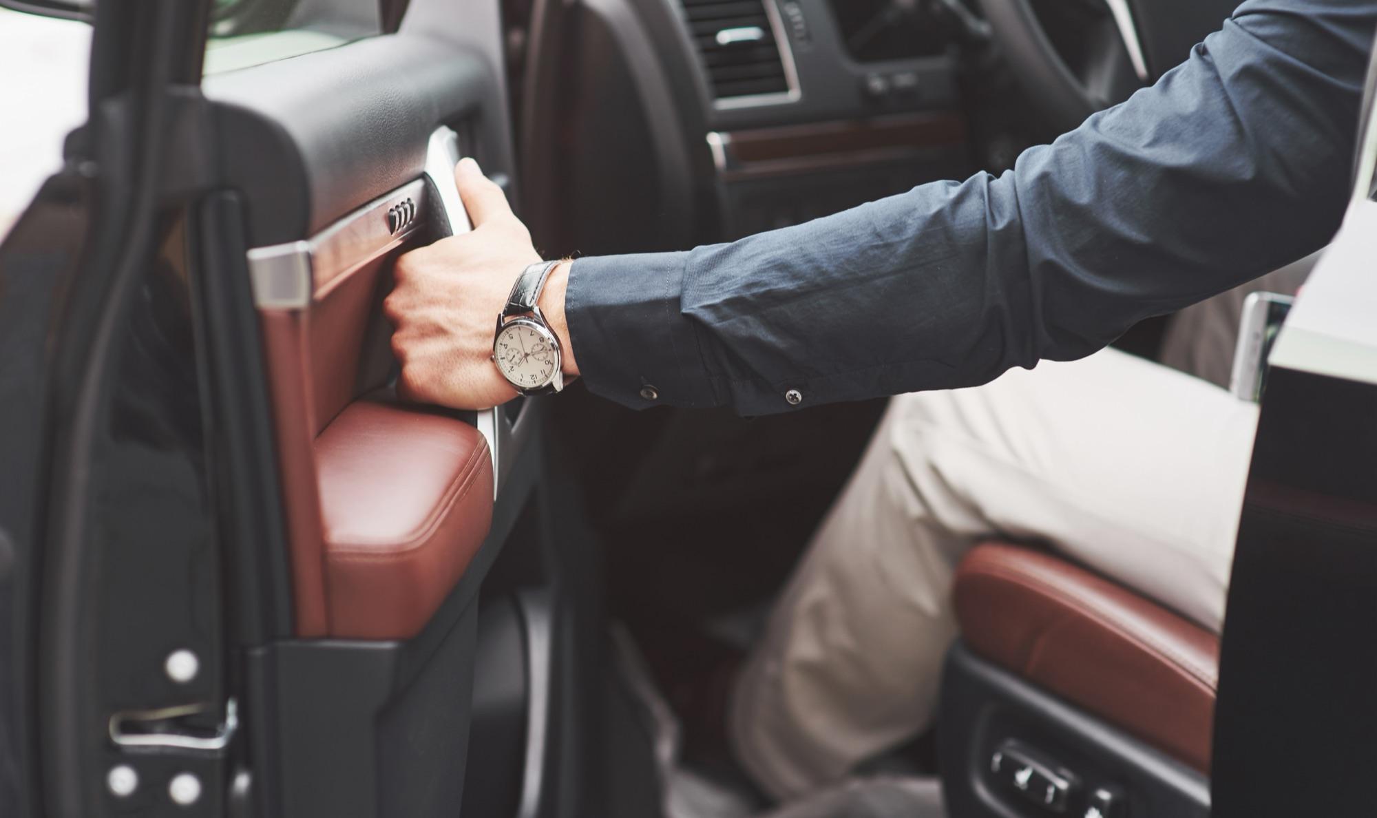 Chauffeur in a tailored suit opening the door of a luxury car